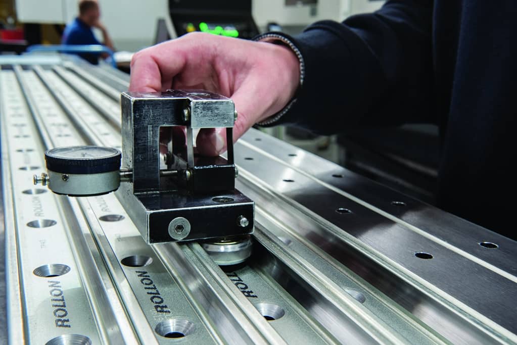 Someone holding a measurement device against fabricated metal pieces 